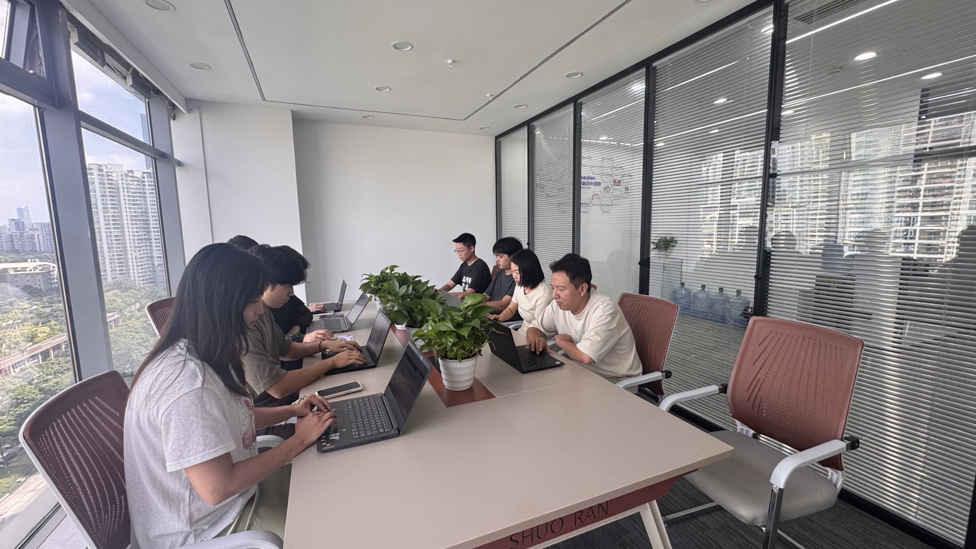 九序团队在会议室开项目例会,每人面前放着笔记本电脑